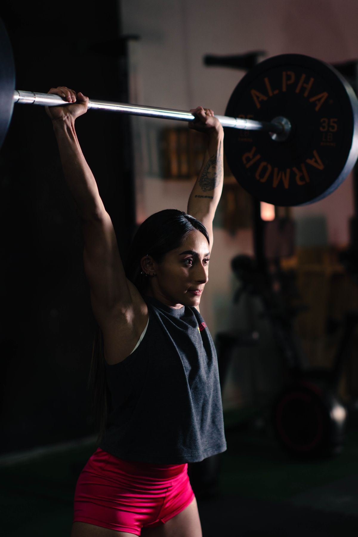 Woman performing an overhead barbell press in a gym
