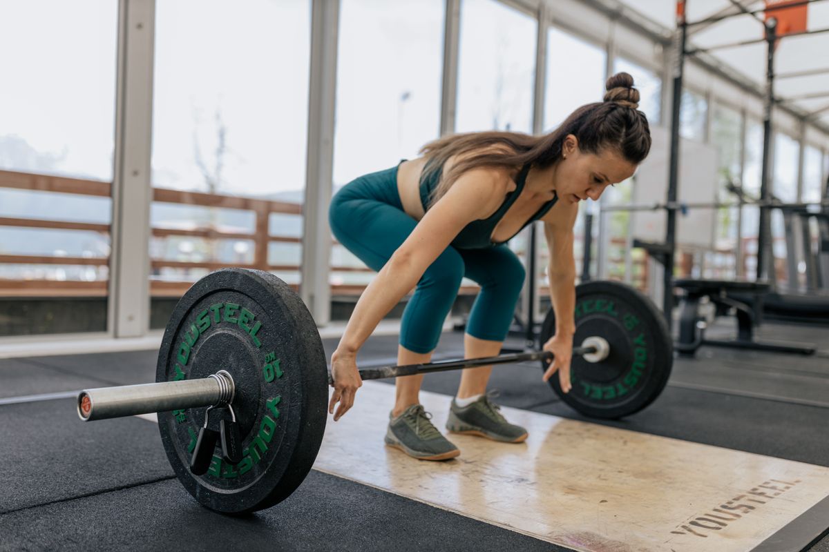 Woman setting up for a barbell deadlift in a gym